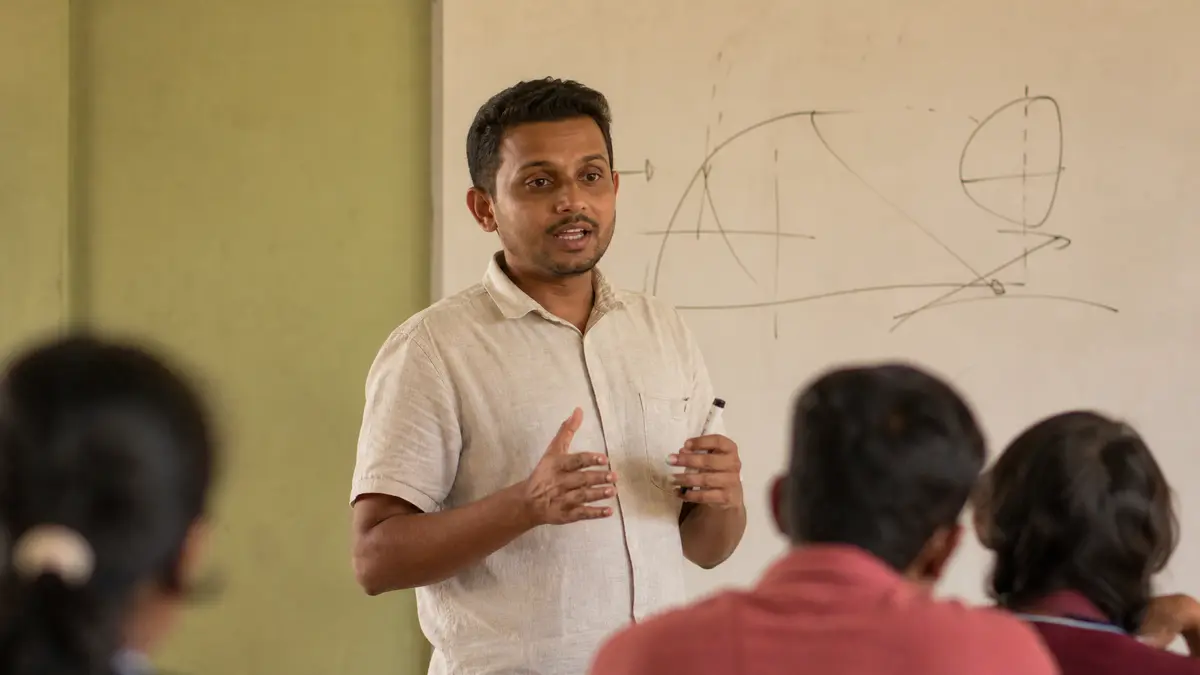 A tuition teacher explaining a diagram at a whiteboard